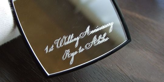 結婚記念日の贈り物に最適な、シャネルのコンパクトミラーに『1st Wedding Anniversary Ryo to Akiko』と名入れ彫刻を施したアップ写真。大切な記念日を祝う、パーソナルで心温まるギフトの細部が際立っています。