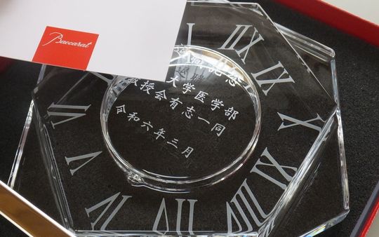 退職記念に贈るバカラ アビスクロック。時計の底面に『退職記念 ○○大学医学部 教授会有志一同 令和六年三月』と漢字で名入れ彫刻された、教授への特別な贈り物