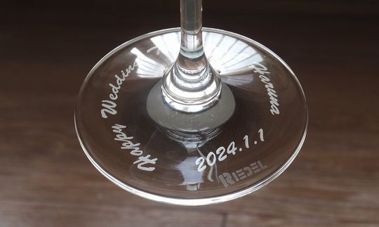 リーデルのシャンパングラスの底面に「Happy Wedding」の文字とお二人の名前、記念日を名入れ彫刻した特別な結婚祝い。高級感のあるデザインが、結婚式の思い出を美しく刻みます