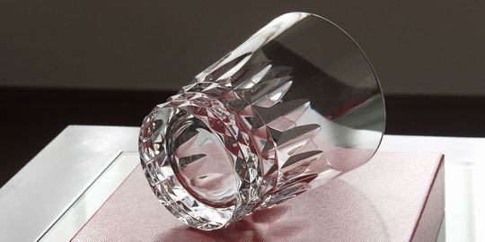 バカラのタンブラー（ロックグラス）の名入れページの商品一覧で使用する写真。バカラ ピカデリータンブラーがテーブルの上に置かれています。大胆なカットが施された美しいクリスタルグラスが光を反射して輝き、名入れギフトとしての存在感と洗練された美しさを演出しています。