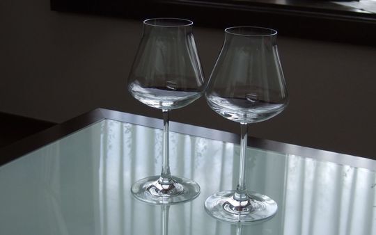 バカラのワイングラス、シャトーバカラワイングラスLを2客、テーブルの上に置いてある写真。丸みを帯びた美しいボウルと、洗練されたデザインが並び、光を反射して輝くクリスタルが、モダンで優雅な食卓の雰囲気を演出しています。
