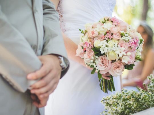 結婚式の写真：新郎新婦の手元をアップで捉えた写真。女性は美しいブーケを持っており、二人の絆と幸せな瞬間が際立っています。