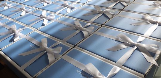 白いリボンが結ばれた大量のウエッジウッドのブランドボックスが整然と並ぶ写真。高級感のある贈答用ギフトの大量注文事例