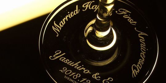 ウェッジウッド ウィズディスリングシャンパングラスの底面に『Married Happy First Anniversary Yasuhiro & Eri 2018.12.3』と名入れ彫刻を施した写真。結婚1周年記念にふさわしい、お二人の名前と日付が刻まれた特別な贈り物です。