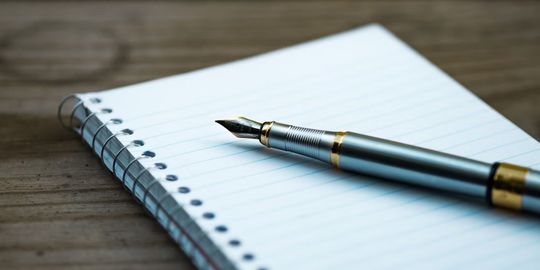 ノートの上にシルバーの高級感のある万年筆が置かれている写真