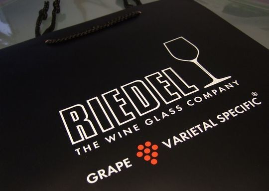 リーデルのロゴが印刷された高級感あるブランドショッパーのクローズアップ写真 ワイングラスギフト用の公式紙袋 デザイン性と品質を兼ね備えた贈答品パッケージ