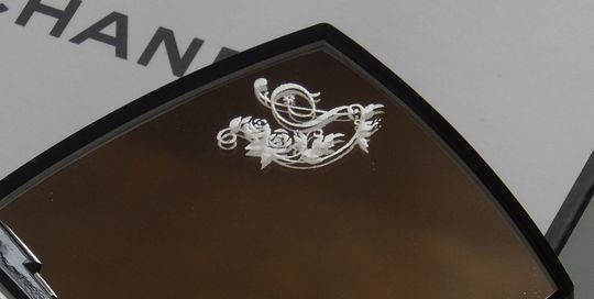 シャネルのコンパクトミラーを開いた際、上部ミラーの左上にイニシャル『S』が名入れ彫刻された写真。鏡を覗くたびに自分のイニシャルが目に留まる、上品でパーソナルなカスタマイズのイメージ。