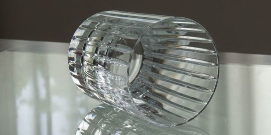 バカラのタンブラー（ロックグラス）の名入れページの商品一覧で使用する写真。バカラ ハーモニータンブラーがテーブルの上に置かれています。縦に伸びるストライプのカットが特徴的なグラスが光を反射して輝き、名入れギフトとしてのシンプルながらも洗練された美しさと特別感を演出しています。