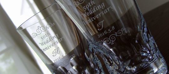 結婚50周年（金婚式）記念に贈る、バカラ ベルーガ ハイボールペアグラス。それぞれのグラス側面に「50th Wedding Anniversary」、お二人のイニシャルと記念日、そして上品な装飾デザインが名入れ彫刻された写真