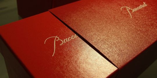 バカラのタンブラー（ロックグラス）の名入れページの商品一覧で使用する写真。異なるシリーズのタンブラーグラスが2個、まるでペアセットのように見えるスリットが入ったギフトボックスに収められています。それぞれのグラスが独自のカットと輝きを放ちながらも、名入れギフトとしての統一感と特別感を演出しています。贈る相手の個性や好みに合わせて、お好きな組み合わせを選べることを示唆する、洗練されたプレゼンテーションです。