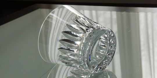 バカラのタンブラー（ロックグラス）の名入れページの商品一覧で使用する写真。バカラ ティアラタンブラーがテーブルの上に置かれています。ティアラのような繊細なカットが施されたグラスが光を反射して輝き、名入れギフトとしての華やかさと特別感を演出しています。