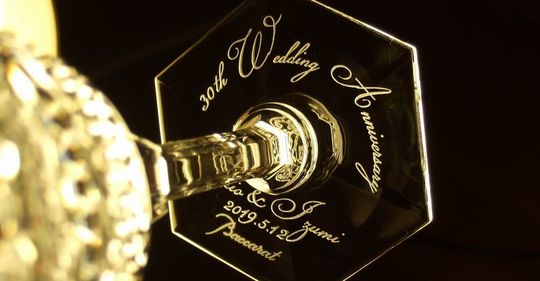 バカラのシャンパングラス、アルクール イブ シャンパングラスの底面に、『30th Wedding Anniversary 二人の名前 2019.5.12』などを名入れ彫刻したアップ写真。象徴的なアルクールデザインのグラスの底に、結婚30周年を祝う特別なメッセージと記念日が繊細に刻まれ、特別な贈り物としての価値と、永続的な愛を象徴する美しさを際立たせています。