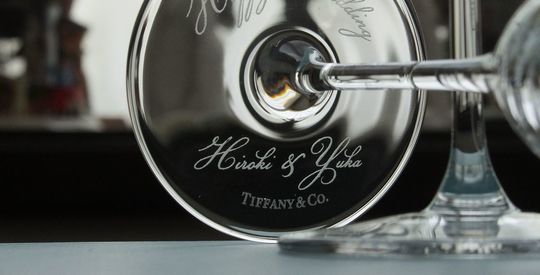 ティファニー ホームエッセンシャル シャンパンフルートの底面に「Happy Wedding」と新郎新婦の名前が彫刻された、結婚祝いに最適な名入れギフト。