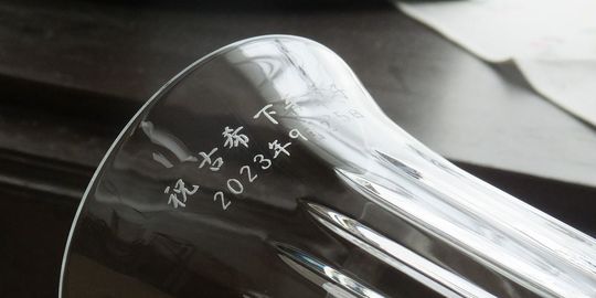 バカラの花瓶、フローラ ベース ビゾーの側面に、『祝 古希 名前 2023年9月25日』と名入れ彫刻した写真。滑らかな曲面と美しいカットが施された花瓶に、古希のお祝いメッセージと日付が丁寧に刻まれています。人生の特別な節目を祝う、記憶に残る特別な贈り物にふさわしい逸品です。