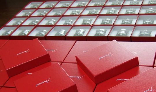 バレーボールJTサンダーズの優勝記念として、名入れ彫刻を施したバカラグラスの複数写真。チームロゴとメッセージ入りの記念グラスがレッドボックスに収納された高級ギフトセット