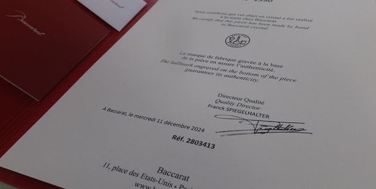 バカラの招き猫 クリアMサイズがテーブルの上に置いてある写真。透明なクリスタル製の招き猫が、その美しいフォルムと光の反射で、空間に幸運と洗練された雰囲気をもたらしています。名入れギフトとしても、インテリアとしても魅力的な逸品です。