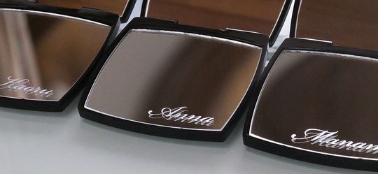 スクリプト体で名前が彫刻されたシャネルの名入れミラーが3つ横に並んだ写真。高級感とオーダーメイドの特別感が伝わる上質なギフトシーン。