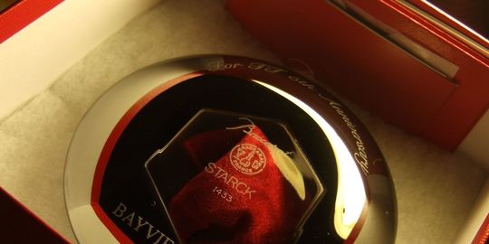 バカラのクリスタル製キャンドルホルダー、アワファイアーがレッドボックスに入っている写真。キャンドルの炎を美しく反射させる、特徴的なフォルムのホルダーが、バカラの象徴的な赤い箱に収められ、贈り物としての高級感と特別感を際立たせています。