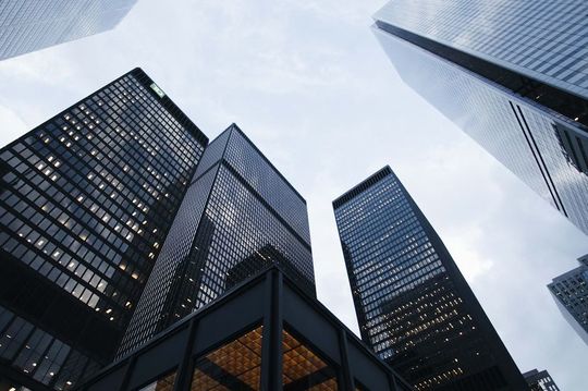 高層ビルを下から見上げる視点。ビジネスでの成功と一旗揚げる決意を象徴する壮大な建物の姿