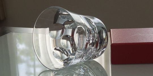 バカラのタンブラー（ロックグラス）の名入れページの商品一覧で使用する写真。バカラ ベルーガタンブラーがテーブルの上に置かれています。キャビアの粒を思わせる丸いカットが特徴のグラスが光を反射して輝き、名入れギフトとしてのモダンな美しさと特別感を演出しています。