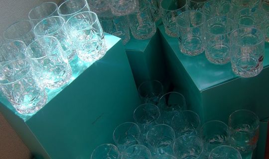 ティファニーのロックグラスがティファニーブルーボックスの上に多数並び、底面に記念の名入れ彫刻が施された写真 高級感あるオーダーメイド記念品の大量注文イメージ