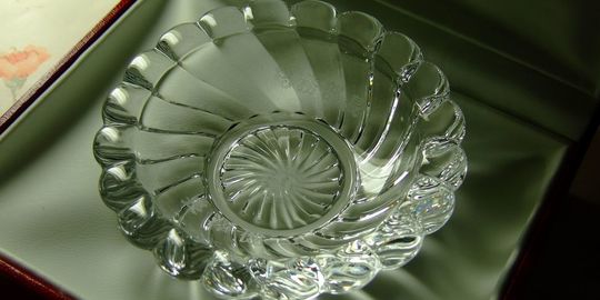 バカラの招き猫 クリアMサイズがテーブルの上に置いてある写真。透明なクリスタル製の招き猫が、その美しいフォルムと光の反射で、空間に幸運と洗練された雰囲気をもたらしています。名入れギフトとしても、インテリアとしても魅力的な逸品です。