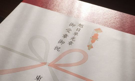 旭日単光章の受章祝い用として、バカラのレッドボックス包装紙に“御受章御祝”と記した熨斗をかけた正式な贈答品