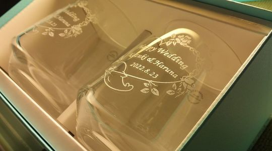 ティファニータンブラーの側面に、ご兄弟が手書きで描いたオリジナルデザインの中に「Happy wedding」の文字とお二人の名前、記念日を名入れ彫刻した特別なギフト。心温まる個性的なデザインが、結婚式の思い出を永遠に残します