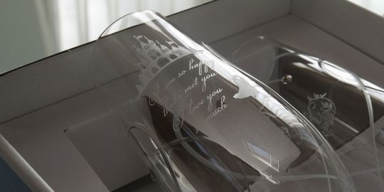 ウエッジウッドのプロミシス・トゥー・ハーツ シャンパングラスの側面に、お城と新郎新婦のシルエット、祝福のメッセージを名入れ彫刻した写真。結婚祝いにふさわしいロマンチックなデザインが刻まれた、特別なウェディングギフト