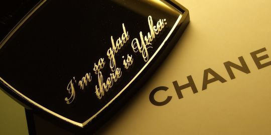 シャネルのコンパクトミラーに『I'm so glad there is Yuka』と名入れ彫刻を施した写真。大切な人への感謝や愛情を伝える、パーソナルで心温まるギフトの細部が際立っています。