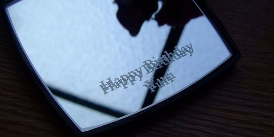奥様の誕生日プレゼントに最適な、シャネルのコンパクトミラーに『Happy Birthday Yuri』と名入れ彫刻を施したアップ写真。大切な方への想いが込められた、パーソナルで心温まるギフトの細部が際立っています。