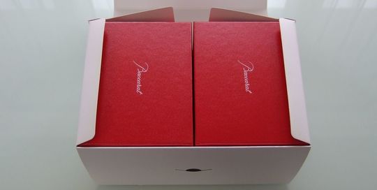 バカラの招き猫Sサイズの特別仕様ペア箱の写真。二つのレッドボックスが白い箱に入っています。バカラの象徴的な赤い箱が2つ並び、それをさらに白い外箱が包み込むことで、ペアギフトとしての高級感と特別感を際立たせています。