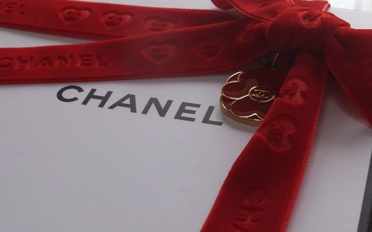 奥様・彼女の誕生日プレゼントに シャネル ギフトボックスのアップ写真 赤い特別リボンとシャネルマーク入り花びらチャーム