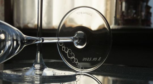 ティファニーのホームエッセンシャルシャンパングラスのペアの底面に、ハートが連なるデザインと『2025.10.8』を名入れ彫刻した写真。エレガントなフォルムのグラスに、二人の愛を象徴するデザインと、記念日が丁寧に刻まれています。大切な二人の結婚記念日を祝う、心に残る特別な贈り物です。