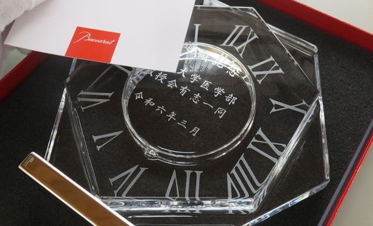 バカラのアビスクロックに大学医学部教授会有志一同より贈る退職記念の名入れ彫刻を施した置き時計。記念日と大学名を刻印したオーダーメイドギフト