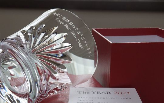 バカラグラスの商品一覧写真。バカライヤーグラス ルテシアタンブラー2024の側面に、『教授就任おめでとうございます！ Enjoy Your New Stage!』と名入れ彫刻を施したグラスが、鮮やかなレッドボックスの上に置かれています。特別な節目を祝う、記念品としての輝きとメッセージが際立つ一枚です。