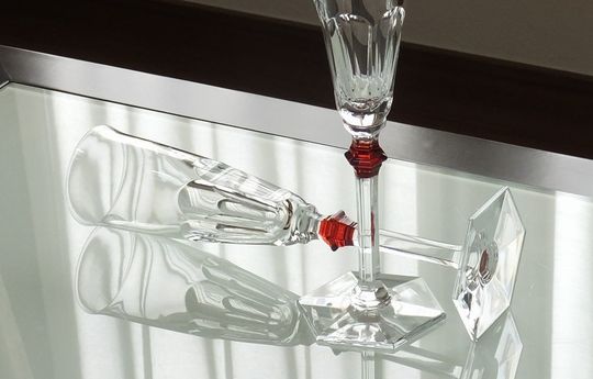 バカラのシャンパングラス、アルクール イブ シャンパングラス（レッド）を2客、テーブルの上に置いてある写真。象徴的なアルクールデザインに、鮮やかなレッドクリスタルが組み合わされ、祝宴のテーブルに情熱的で華やかな彩りを添えています。