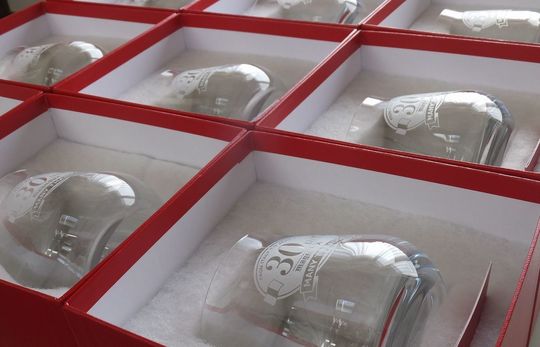 30周年記念デザインが施されたバカラのシャトータンブラー複数個がレッドボックスに収められたオリジナル名入れ彫刻入りの記念品の写真