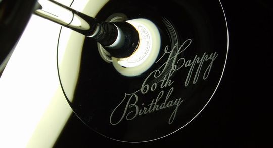 バカラのワイングラスの底面にスクリプト体で「Happy 60th Birthday」の文字が名入れ彫刻された、特別な誕生日を祝う豪華なクリスタルギフト。洗練されたデザインが60歳の記念日を華やかに演出します