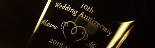 バカラハイボールグラスの側面に「10th Wedding Anniversary」の文字とお二人の名前でオリジナルのハートデザインを挟んだ名入れ彫刻。愛と絆を祝う特別な10周年記念の贈り物