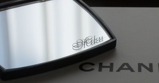 シャネルのコンパクトミラーの下部ミラーに『Miku』と名入れ彫刻が施された写真。ギフトでのオーダーをイメージさせる、洗練されたパーソナライズアイテムの紹介。