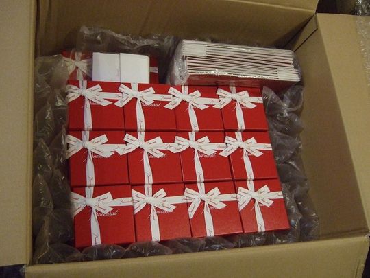 バカラのレッドボックス12個が段ボールに綺麗に収納され、エアクッションで保護された配送準備の写真 高級ギフトの安全な発送事例