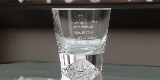 富士山ロックグラスの側面に、『in commemoration of retirement mar.29 2024 from all the members』と名入れ彫刻した写真。グラスの底に富士山がデザインされた美しいロックグラスに、退職を祝うメッセージと日付が丁寧に刻まれています。日本らしいデザインで、特別な節目を祝う贈り物にふさわしい逸品です。