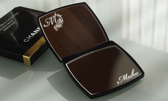 シャネルのコンパクトミラーの上部ミラーに大きくイニシャルの『M』、下部ミラーに『Mako』と名入れ彫刻を施した写真。上下それぞれのミラーに刻印を分けることで、ブランドの気品とパーソナライズの特別感が共存した贅沢なデザイン。