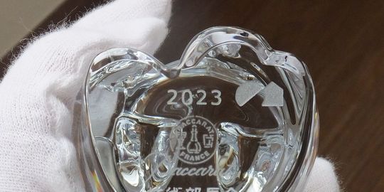 バカラの招き猫 クリアSの底面に、『2023』と積水ハウスのロゴデザインを名入れ彫刻した写真。透明なクリスタル製の招き猫の底に、年号と企業のロゴが繊細に刻まれています。企業やイベントの記念品、または特別な贈り物として洗練された逸品です。