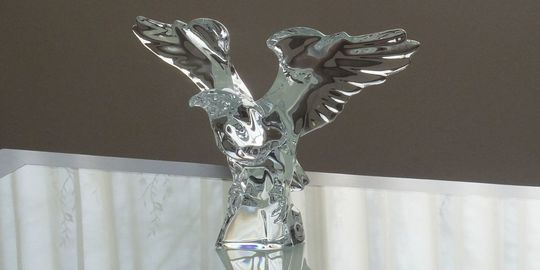 バカラのアメリカンイーグルがテーブルの上に置いてある写真。鋭い眼光と力強い翼を持つ鷲の姿が、クリスタルの透明感と光の反射によって、威厳のある美しいフォルムを際立たせています。名入れギフトとしても、成功や飛躍を願う特別な贈り物としても最適です。