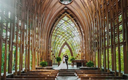 森の中のガラス張りチャペルで寄り添う新郎新婦の笑顔｜結婚祝いにふさわしい上質な名入れギフトを贈る特別な瞬間