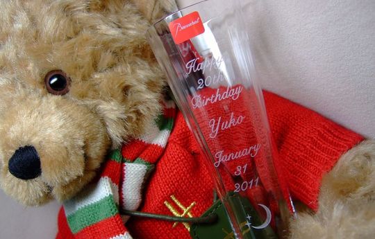 バカラのシャンパングラス、ミルニュイシャンパングラスの側面に、『Happy 20th Birthday Yuko January 31 2011』の文字と、月のデザインなどを名入れ彫刻した写真。グラスの繊細なカットと、二十歳の誕生日を祝うメッセージ、そしてロマンチックな月のデザインが美しく調和し、特別な記念のグラスとなっています。