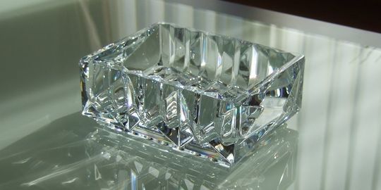 バカラの小物入れ、ルクソールトレイがテーブルの上に置いてある写真。ピラミッドのような幾何学的なカットが施されたトレイが、光を反射して輝き、鍵やアクセサリーなどを置く小物入れとして、空間にモダンで洗練された美しさを添えます。名入れギフトとしても最適な贈り物です。