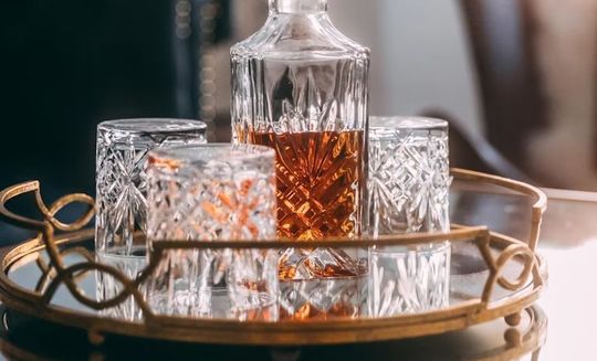 バカラのタンブラー（ロックグラス）の名入れページの商品一覧で使用する写真。タンブラーとデカンタが並んでいる写真です。重厚なクリスタル製のデカンタと、それに合わせてデザインされたタンブラーが共に置かれ、ウイスキーやブランデーなどの蒸留酒を楽しむための完璧なセットアップを演出しています。名入れギフトとしての統一感と、上質な時間を贈るというメッセージを伝えています。